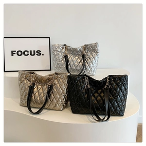 Quilted metallic tote bags in silver, gold and black colors displayed on a podium