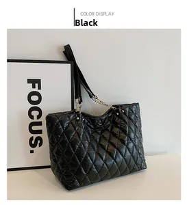 Detail of black quilted tote bag with glossy nylon finish and gold chain straps