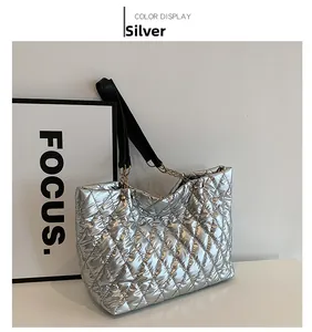 Detail of silver quilted tote bag with metallic finish and black leather chain strap