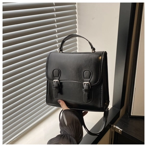 Detail view of a black vintage PU leather handbag with silver buckles and a top handle
