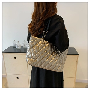 Detailed back view of a silver metallic quilted puffer tote bag on a fashion model