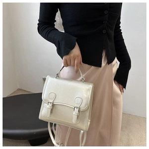 Close-up of pearl white leather backpack with buckle details worn by a model