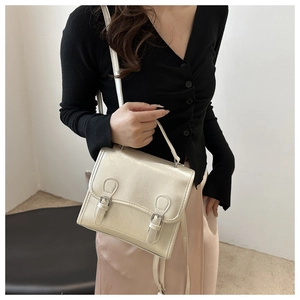 Detail view of retro cream PU leather square bag with metallic sheen and buckle accents