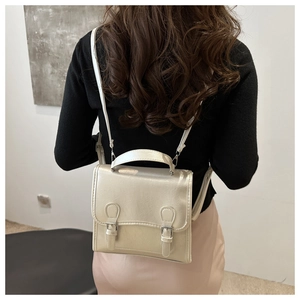 Detail view of champagne gold textured PU leather backpack with buckle straps and handle