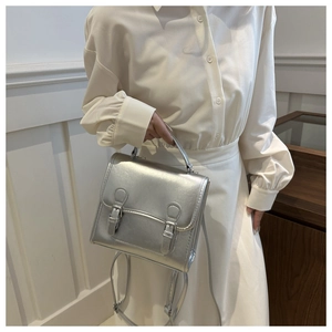 Silver metallic mini crossbody bag with double buckle straps shown on a model