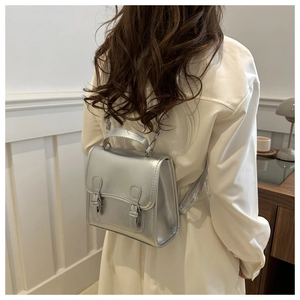 Silver PU leather mini backpack in Cambridge style shown on model in a soft home setting