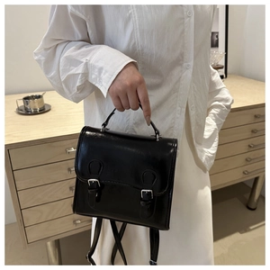 Detail of black leather mini backpack with dual buckle design and top handle