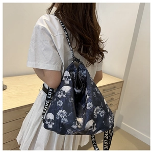 Detail of large floral skull tote bag with LOVE lettered shoulder strap on model