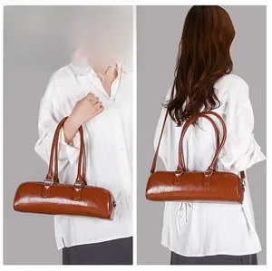 Detail of caramel brown faux leather boston bag with glossy finish and top zip closure