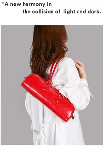 Detail of red patent leather cylinder bag showing high-gloss finish and slim shoulder strap
