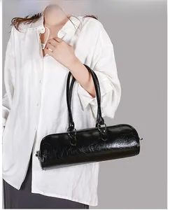 Close-up of black wrinkled oil leather baguette bag with silver hardware on model