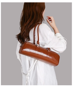 Detail view of brown glossy cylindrical shoulder bag with retro leather texture