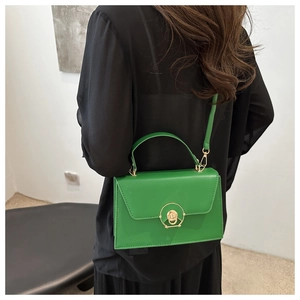Detail of bright green crossbody bag featuring a golden round rotating clasp and matte finish