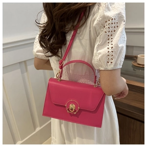 Detail of fuchsia square crossbody bag featuring golden circular twist lock and handle