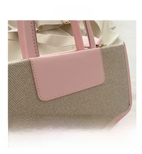 Close-up of pink leather stitching and beige textured woven fabric on a tote bag