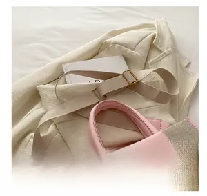 Detail of wide adjustable strap and pink leather handle on a woven canvas tote bag