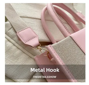 Close-up of golden hardware hooks on pink leather and beige canvas woven tote bag