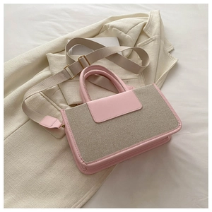 Detail of pink leather trim and textured woven fabric on a stylish tote handbag