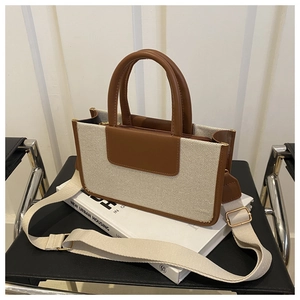 Detail of canvas tote bag with brown leather trim and detachable woven shoulder strap