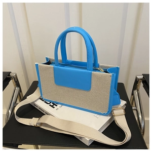 Detail of canvas and blue leather tote bag with wide strap and zip closure