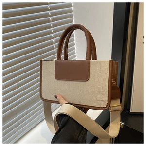 Detail of canvas and brown leather tote bag with wide strap and golden metal hardware