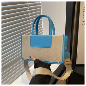 Detail of sky blue leather and beige canvas tote bag with adjustable woven shoulder strap