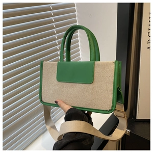 Detail of green canvas tote bag featuring leather handles and wide adjustable strap