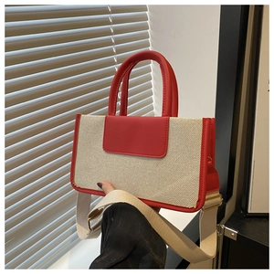 Close-up of contrast stitching detail on red leather and beige woven canvas tote bag