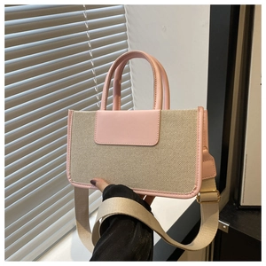 Detail of woven canvas tote with pink leather trim and wide adjustable strap