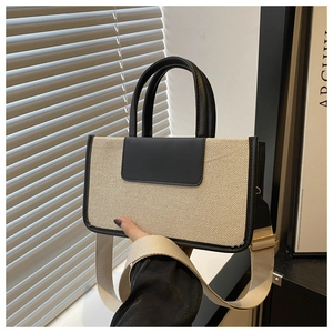 Detail of woven mini tote bag with black leather trim and gold hardware accents