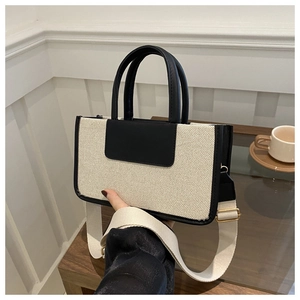Detail of canvas tote bag with black leather trim and adjustable wide fabric strap