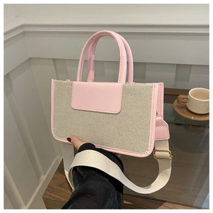 Detailed view of woven canvas tote bag with pink leather trim and wide shoulder strap