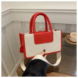 Detail of red and beige woven tote bag with leather trim and wide fabric strap