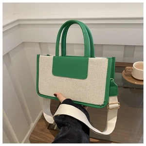 Detail of canvas tote bag with green leather trim and golden metal buckles close-up