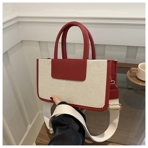 Detailed shot of red and cream canvas tote bag featuring adjustable wide shoulder strap