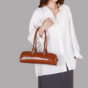 Minimalist dark brown cylindrical baguette handbag with dual handles and glossy leather finish