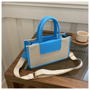 Detail of blue leather trim and beige woven fabric on a rectangular tote bag