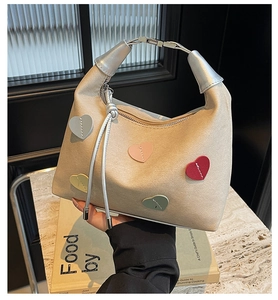 Detail of beige hobo bag with colorful heart patches and silver hardware accents
