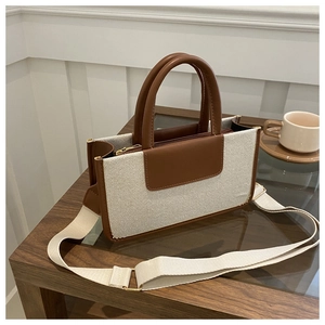 Detail of canvas tote bag with brown leather trim and wide fabric shoulder strap