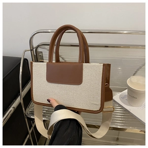 Detail of canvas tote bag with brown leather trim and wide adjustable fabric shoulder strap