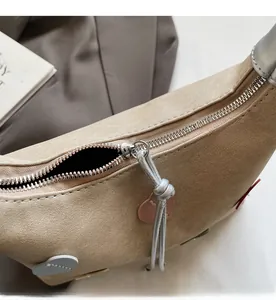 Detail of silver metal zipper with pink heart charm on a beige minimalist handbag