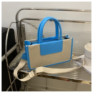Detail view of woven contrast tote bag with blue leather trim and wide canvas strap