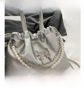 Détail du sac seau argenté métallisé avec chaîne de perles et ornement papillon