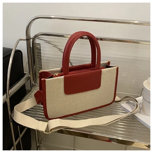 Detail of red leather trim and beige woven canvas texture on a modern tote bag