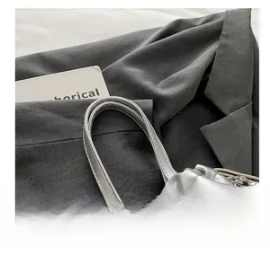 Détail du sac à main plissé argenté avec poignée confortable et breloque chaîne perlée