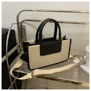 Detail view of woven tote bag with contrast leather trim and wide fabric strap