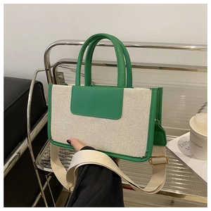 Close-up of contrast woven canvas tote bag with green leather trim and wide shoulder strap