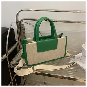 Close-up of green leather trim and cream canvas material on a stylish tote bag