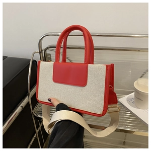 Detail of red leather trim and off-white canvas tote bag with wide strap