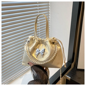 Détail du sac seau en satin blanc cassé avec papillon en métal argenté et chaîne en perles